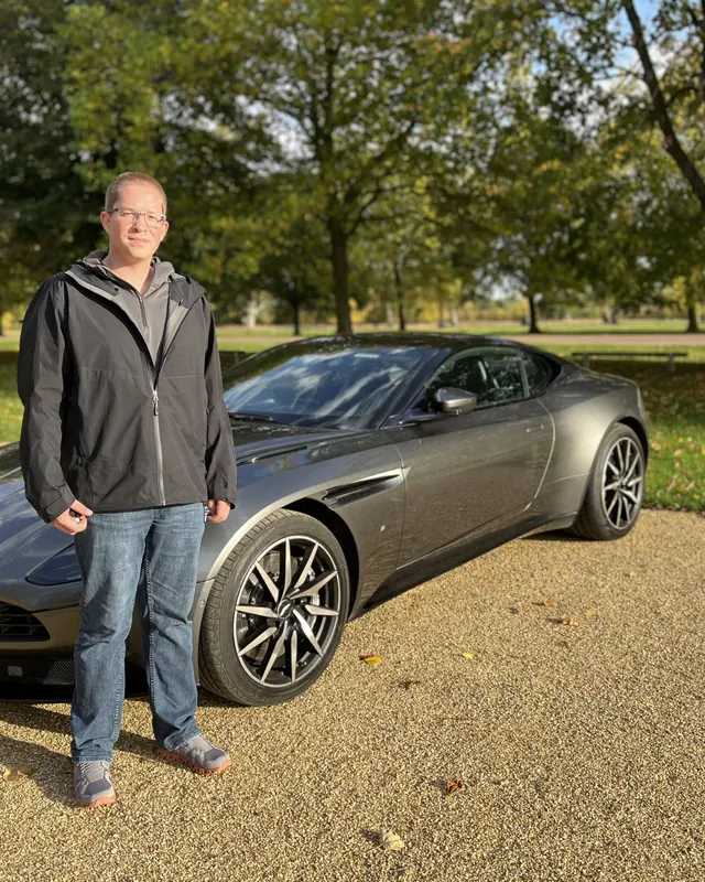 A customer beside an Aston Martin DB11 at a country estate