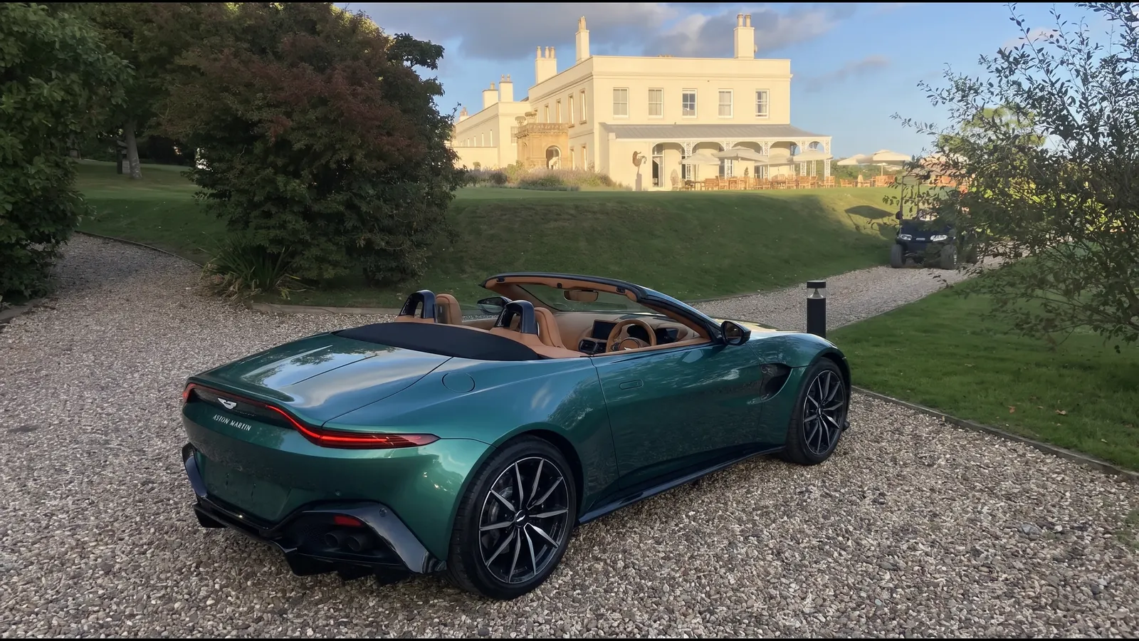 Green Aston Martin Vantage Roadster outside a country house at golden hour