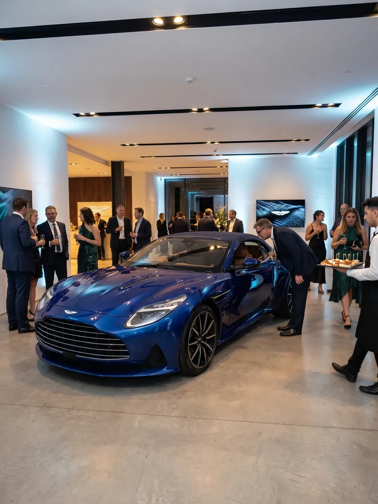 A blue Aston Martin DB12 on display at a launch event