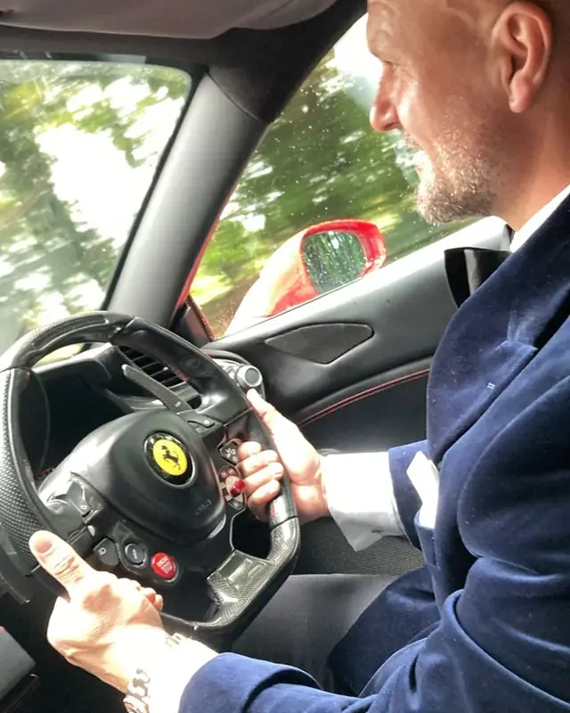 A groom at the wheel of a Ferrari on his wedding day
