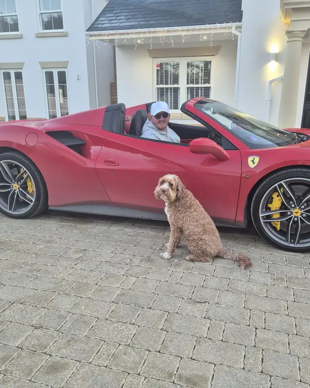 Ferrari 488 Spider on a driveway with a dog sitting beside it
