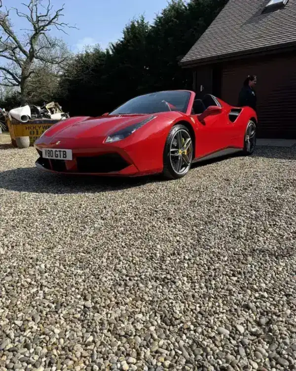 Red Ferrari 488 Spider parked on a gravel drive