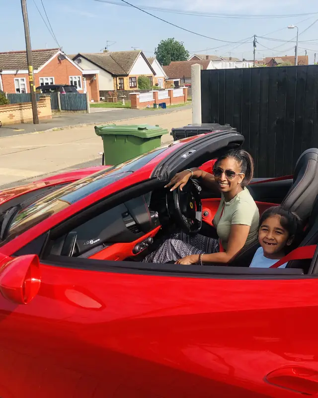 A mother and daughter in the passenger seats of a red Ferrari 488 Spider