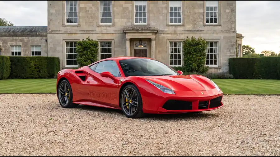Red Ferrari 488 Spider on the gravel drive of an English country house