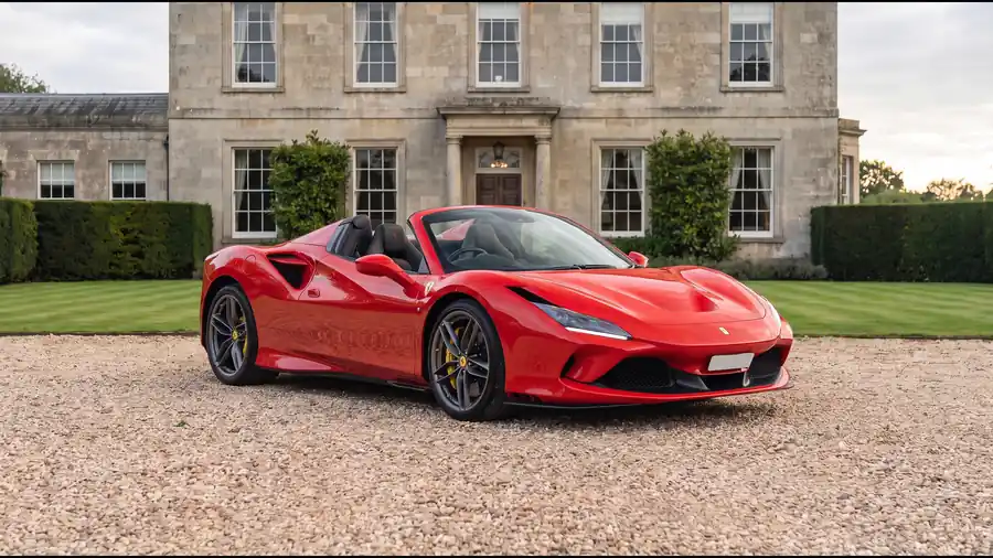 Red Ferrari F8 Spider on the gravel drive of an English country house