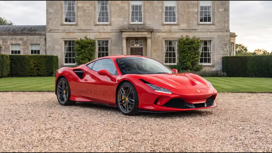 Red Ferrari F8 Tributo on the gravel drive of an English country house