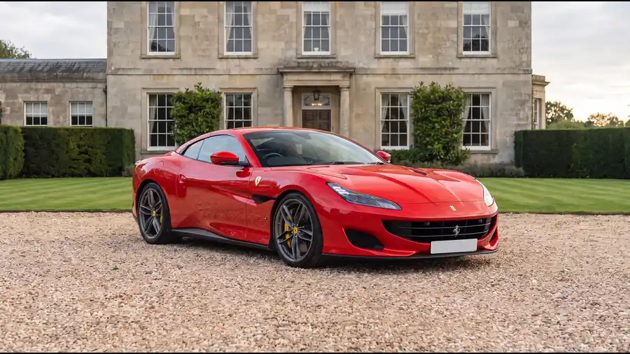 Red Ferrari Portofino M on the gravel drive of an English country house