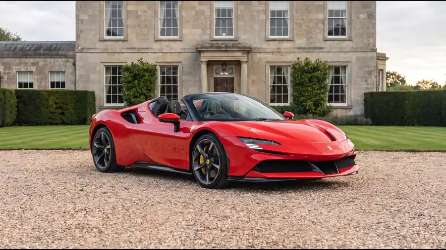 Red Ferrari SF90 Spider on the gravel drive of an English country house