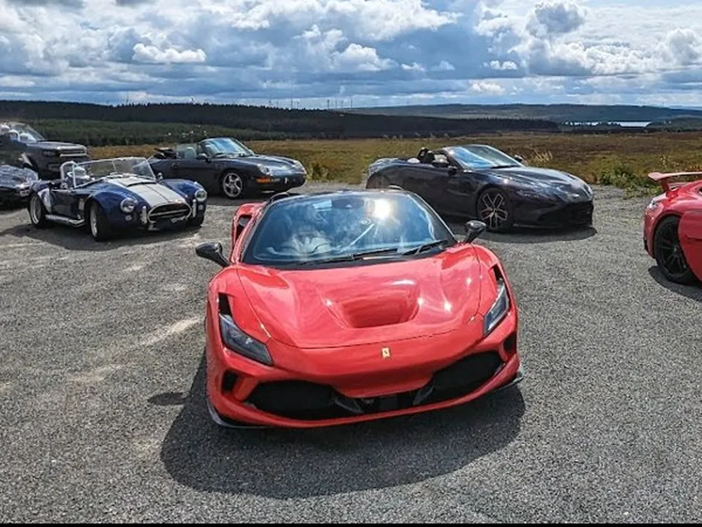 A Ferrari F8 Spider leading a group of supercars on a driving day