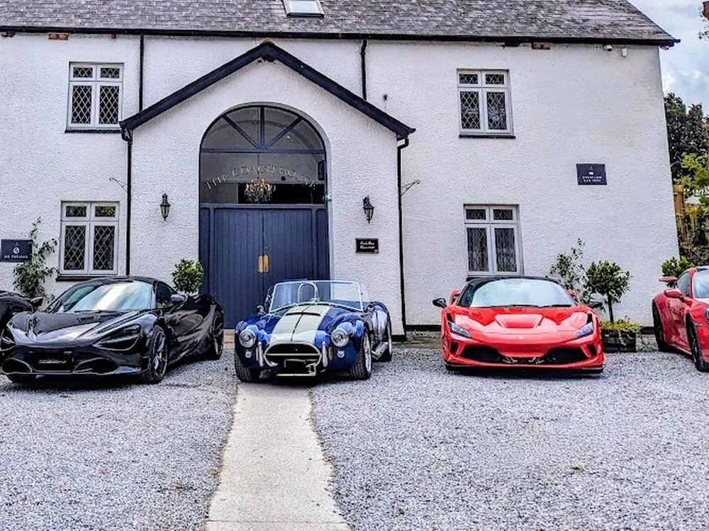 Supercars lined up outside a white country house venue