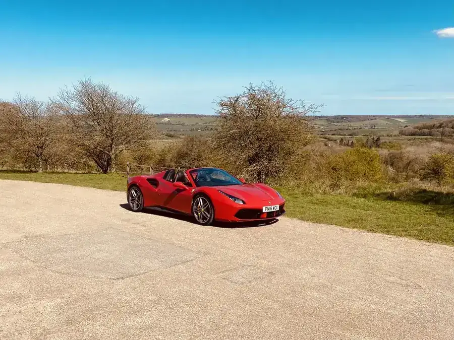 Red Ferrari 488 Spider parked on open heathland under a blue sky