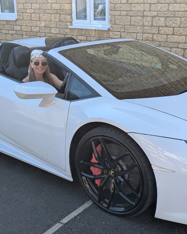 A customer in a white Lamborghini Huracán Spyder with the roof down