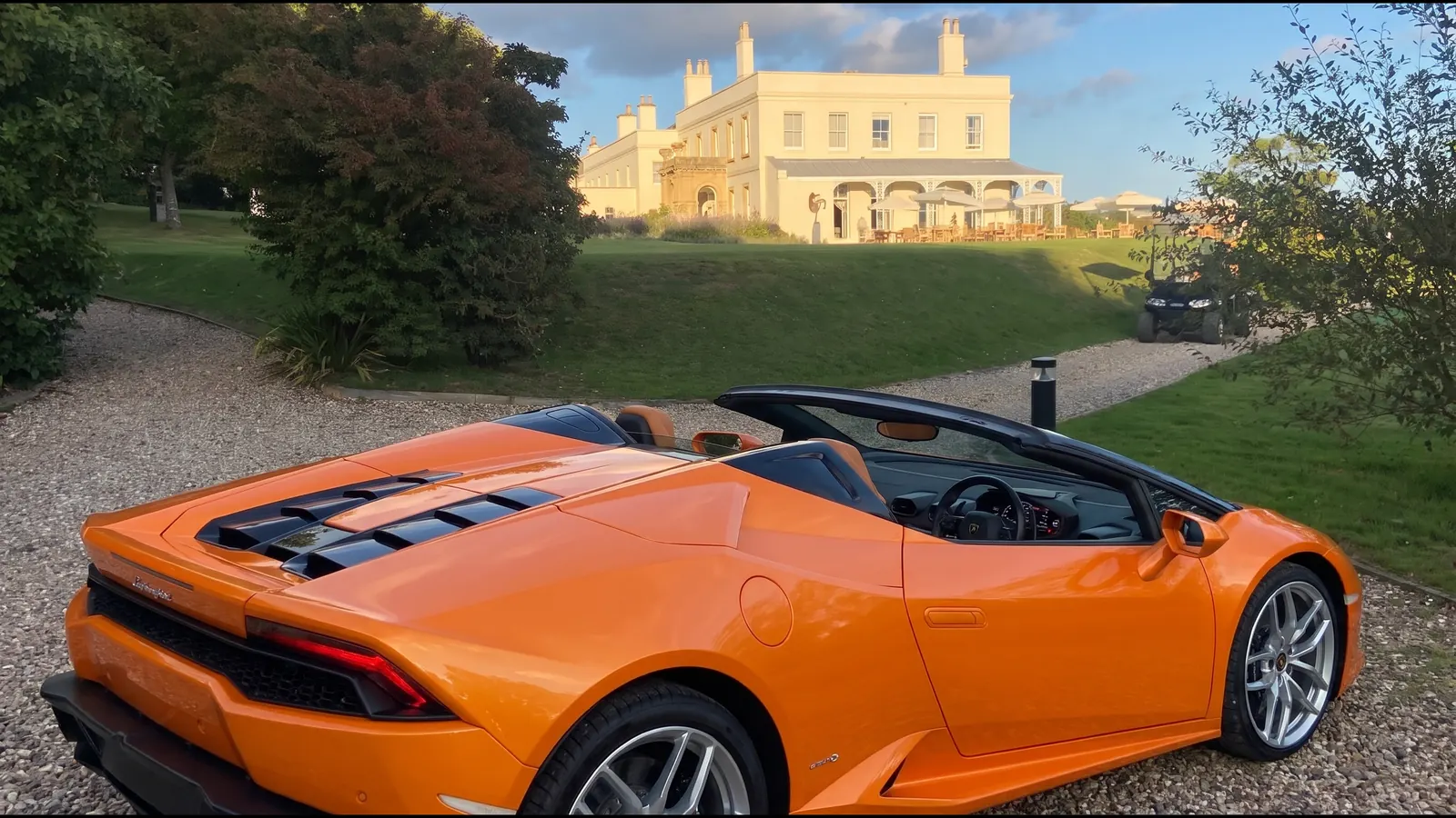 Orange Lamborghini Huracán Spyder outside a country house at golden hour