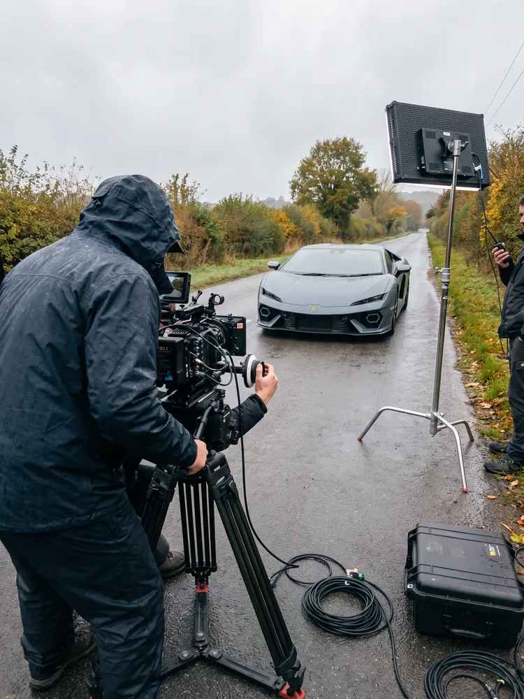 A film crew shooting a grey Lamborghini Temerario on a country road
