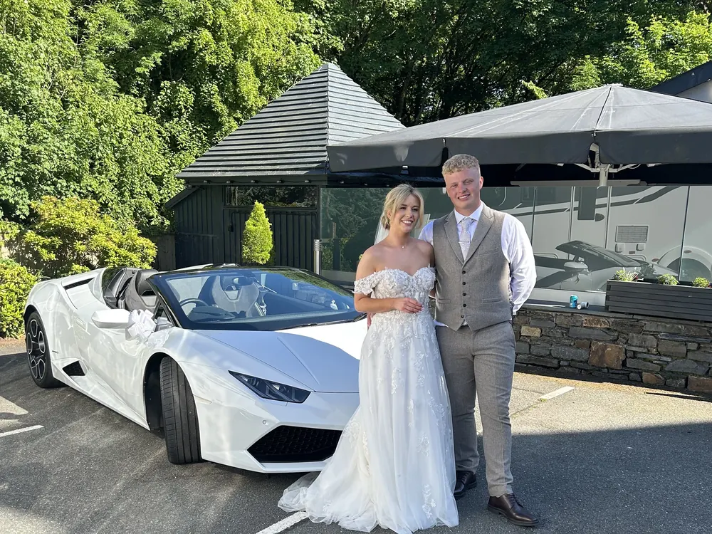 A bride and groom with a white Lamborghini Huracán Spyder