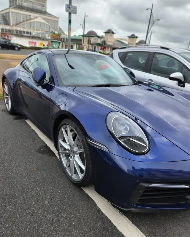Blue Porsche 911 parked on a seafront