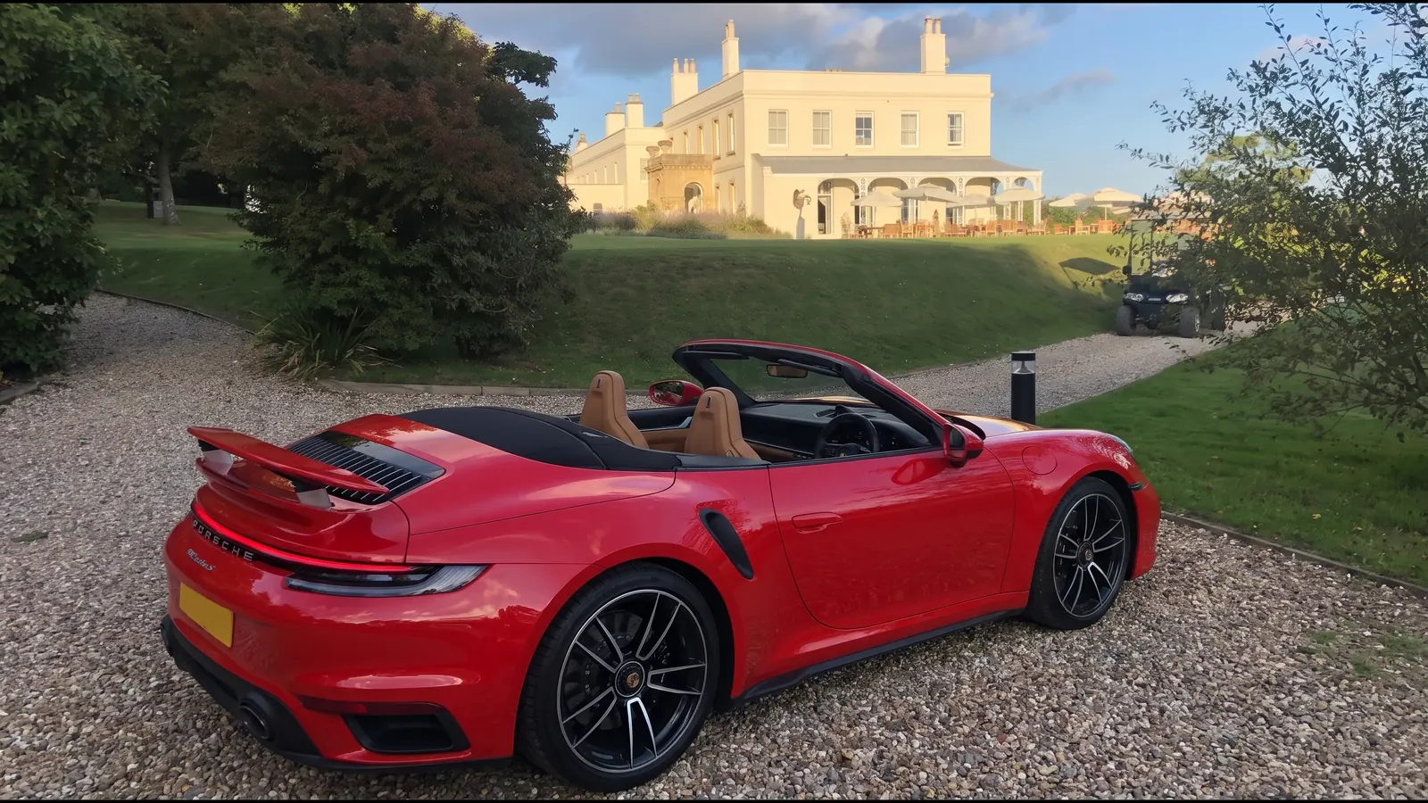Red Porsche 911 Cabriolet outside a country house at golden hour