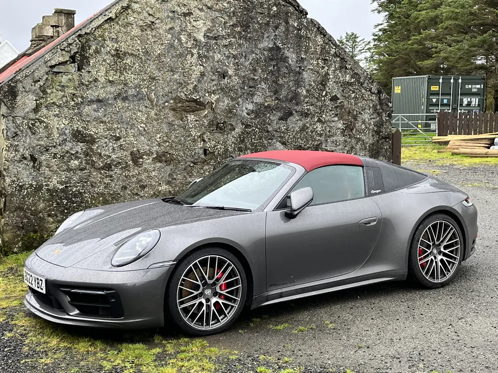 Grey Porsche 911 Targa beside a stone cottage in Scotland